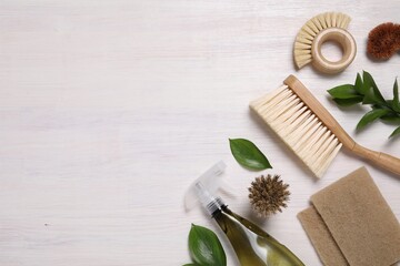 Flat lay composition with different cleaning supplies on light wooden background, space for text