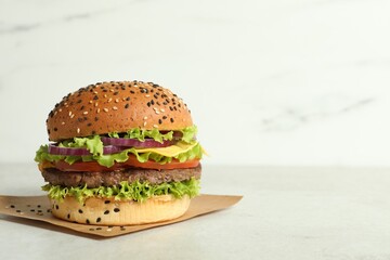 Burger with delicious patty on light table, space for text