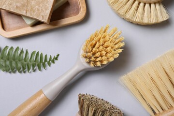 Cleaning brushes, soap and fern leaf on grey background, flat lay
