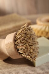 Fototapeta na wymiar Cleaning brush and soap bar on wooden table, closeup