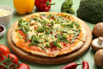 Delicious vegetarian pizza and products on green table, closeup