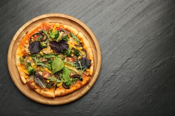 Delicious vegetarian pizza with mushrooms, vegetables and greens on black table, top view. Space for text