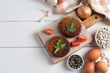 Fototapeta na wymiar Vegetarian product. Tasty bean cutlets served on white wooden table, flat lay. Space for text