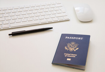 Close up of an American passport on white table, with a computer keyboard and mouse