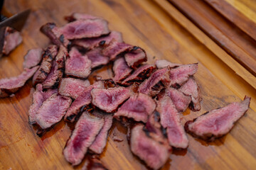Pink cut steak peaces on wooden cutting board after grilling in the summer picnic time, cooked to a perfection as medium rare pieces