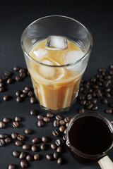 Glass of Frappuccino with ice and glass coffee scoop on dark background