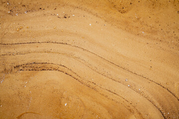 Black mud flowing in the water of yellow sea sand. Mixing good and bad in nature