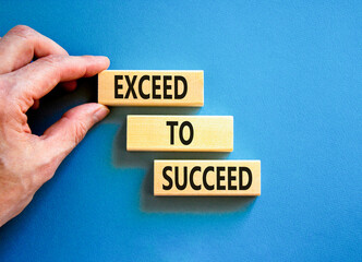 Exceed to succeed symbol. Concept words Exceed to succeed on beautiful wooden blocks. Beautiful blue table blue background. Businessman hand. Business and exceed to succeed concept. Copy space.