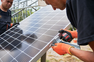 Workers installing solar panel on metal beams. Renewable and ecological energy. Idea of environment safe. Modern technology and innovation. Cropped image of european men wearing workwear and helmets