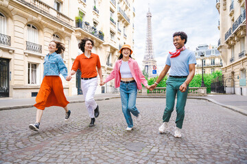 Multiethnic group of young happy friends visiting Paris and Eiffel Tower