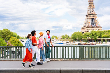 Multiethnic group of young happy friends visiting Paris and Eiffel Tower