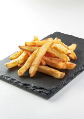 Crisp steakhouse style French Fries with pepper and salt, on slate plate, isolated on white background.