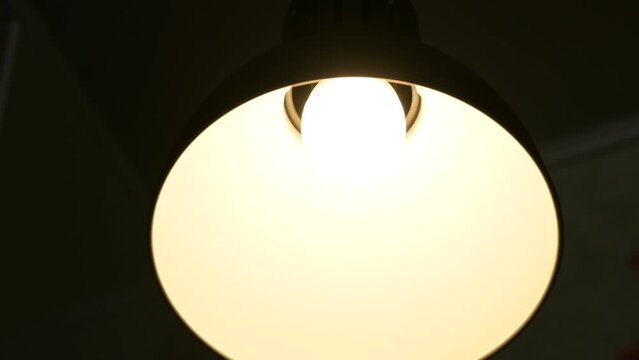 Close-up of a lamp turning on and off light. Modern LED bulb in table lamp, switching on light