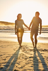 Lens flare, sunset and couple holding hands at beach, ocean and sea with affection, bonding and...