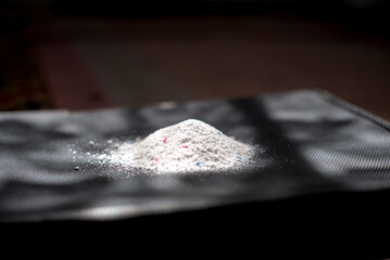 Pile of laundry detergent powder isolated on dark surface