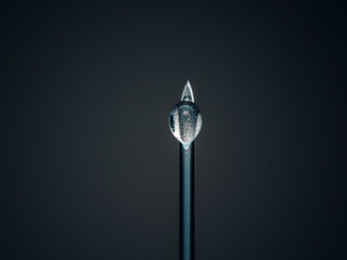 vertical shot of black needle with drop
