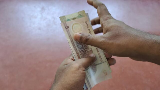 Person hand counting united arab emirates dirham currency note. Closeup top view.