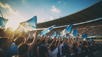 group of fans dressed in blue color watching a sports event in the stands of a stadium - obrazy, fototapety, plakaty