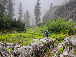 Man hike alone though the Bavarian mountains and he use a trash bag as his rain water protection