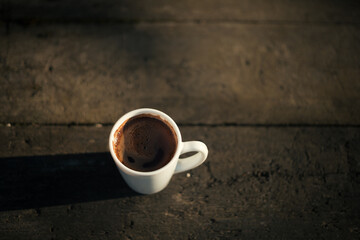 a cup of coffee stands on a wooden table in the garden