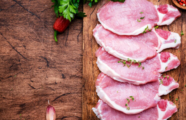 Raw pork chops on wooden board prepared for cooking with spices and pepper. Wood kitchen table background,  top view - 783074618
