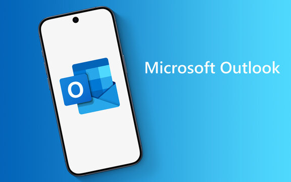 Outlook Logo is displayed on a modern smartphone, laying on a blue underground with Microsoft Outlook lettering, email client, with functions as calendaring, task managing, contact managing, notes
