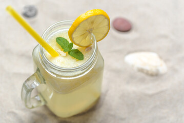 Fresh lemon drink with straw. Jar glass of lemonade on sand beach. - 783081278
