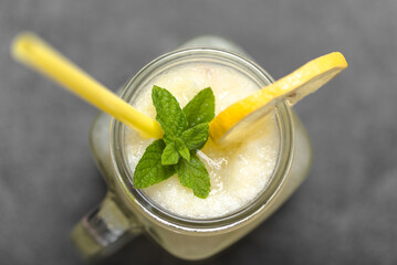 Fresh summer drink with straw. Jar glass of lemonade with lemons and mint on dark background. - 783081447