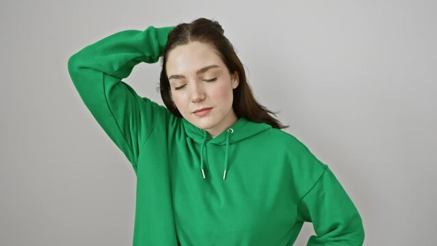 Attractive young woman in fashionable sweatshirt posing with gleaming smile, confidently touching hair while standing, injecting joy and style to the isolated white background