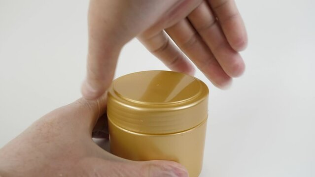 A cosmetic gel from a plastic jar is applied to a wooden spatula.