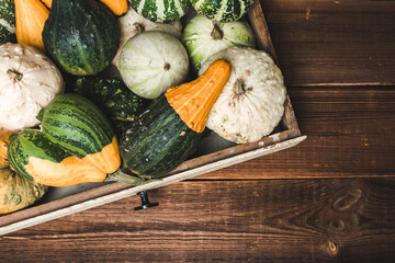 Fresh pumpkins in the box on wooden background. Decorative vegetables harvest. Autumn Thanksgiving background. - 783085685