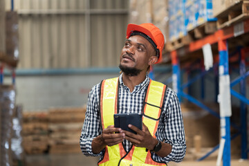 Male warehouse worker holding tablet during working in storage warehouse. Warehouse worker...