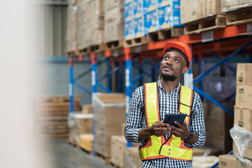 Male warehouse worker holding tablet during working in storage warehouse. Warehouse worker...