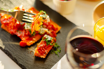 Four cheese filled ravioli in a tomato and basil sauce on the black stone plate - 783087827