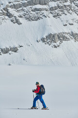 Fototapeta na wymiar A female skier stands at the snowy summit of a mountain, equipped with professional gear and skis, poised for an exhilarating descent.