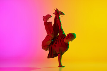 Cool attitude young man, talented dancer dancing in motion in neon light against gradient...