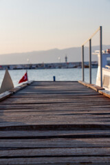 Fototapeta premium Wooden pier on the background of the sea and the city. Wooden pier on the shore of a lake with rocks and blue sky