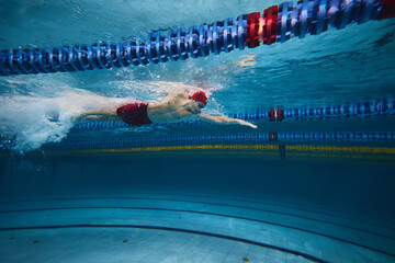 Boundless energy and motivation. Athletic young man, swimmer in cap and goggles in motion training...