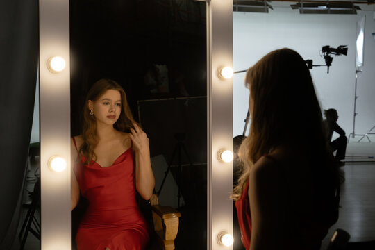 An elegant reflection: Woman in a red dress in the mirror Backstage shot.