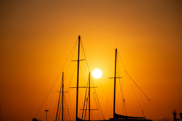 Silhouette of yachts at sunset in the harbor. Silhouette of a sailboat at sunset in the sea.
