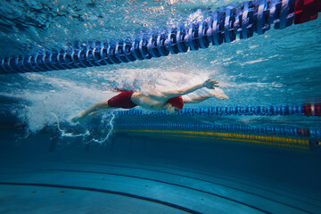 Beauty of athleticism in action. Dynamic image of young man, athlete in motion, swimming in s pool...