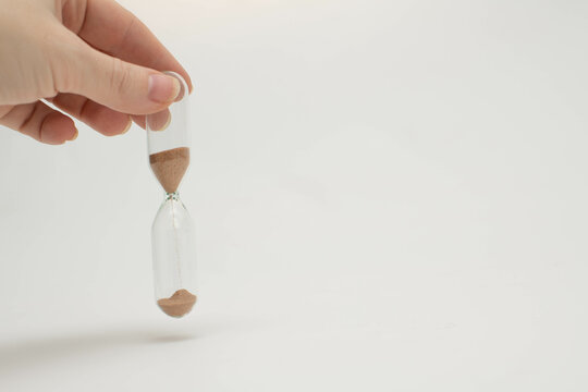 Unrecognizable female hand holding transparent hourglass