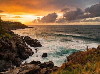 Orange sunrise over the ocean. View from a cliff on a rocky shore.