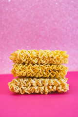 Dry noodles for brewing are stacked on top of each other on a pink background - 783101045