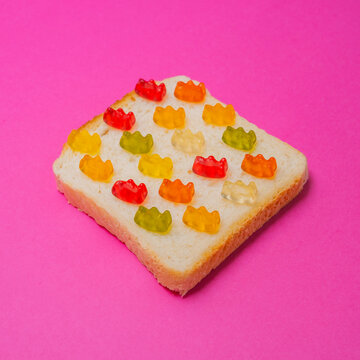 Colorful pieces of marmalade on a slice of bread as a sandwich on pink background