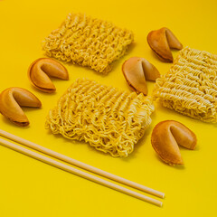 A dried noodles, fortune cookies and chopsticks are laid out on yellow background - 783101846