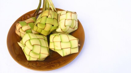 Ketupat (Rice Dumpling) served on plate isolated white. Ketupat is a natural rice casing made from young coconut leaves for cooking rice during Eid Mubarak, copy space