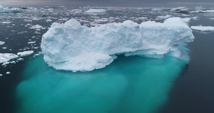 Massive iceberg floating in Antarctica ocean. Snow covered blue ice melting underwater. Ecology, climate change and global warming concept. Antarctica travel and exploration. Aerial drone panorama