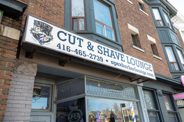 Fototapeta premium exterior building and box light sign of APEX Cut & Shave Barber Lounge, a barber shop, located at 275 Danforth Avenue in Toronto, Canada