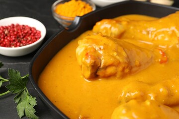 Tasty chicken curry and ingredients on black table, closeup